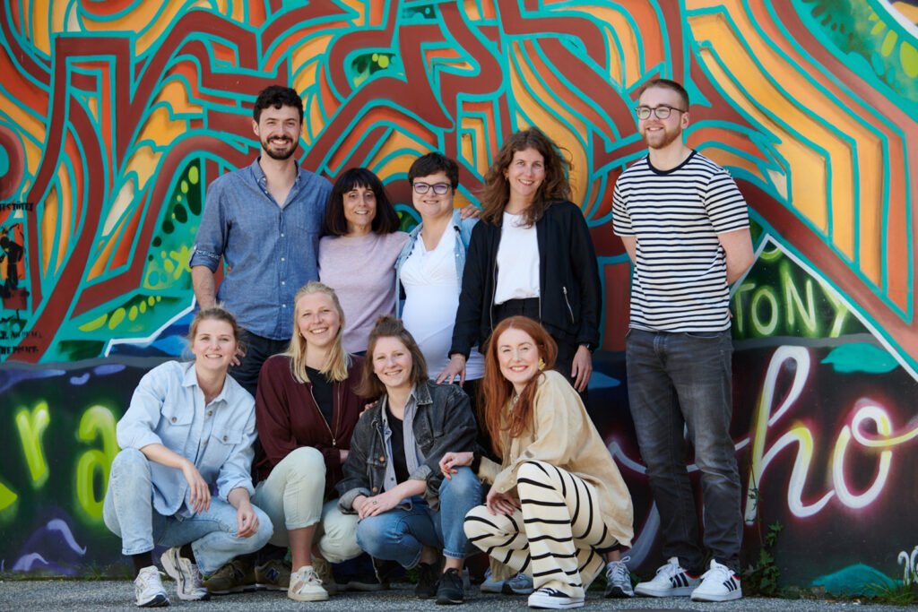 Kolibri group photo in front of a graffiti-covered wall