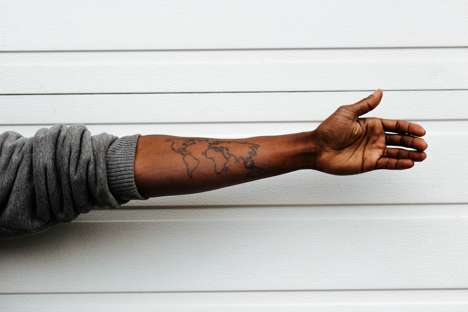 Ausgestreckter Arm mit Weltkarten-Tattoo