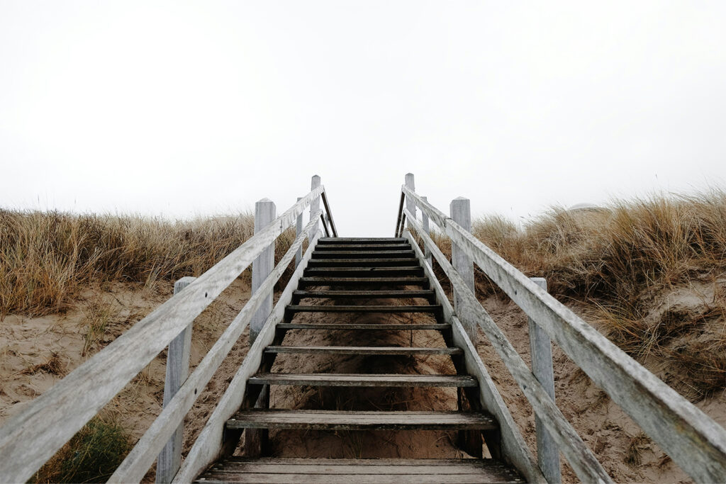 Eine Holztreppe führt die Dünen am Strand hinauf